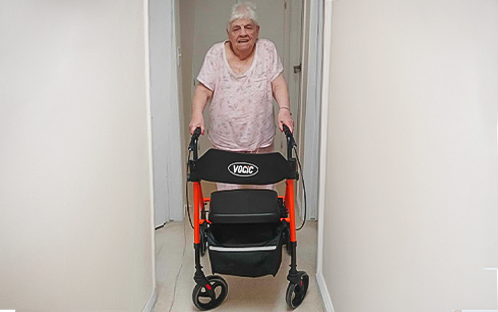 Jim's mom with her orange Z21 rollator walker through the doorway